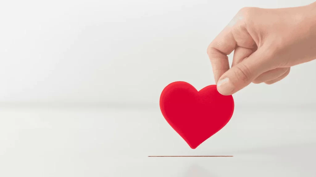 una mano introduciendo un corazon en una urna